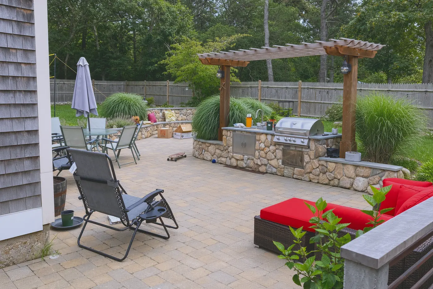 Paver patio with a cedar pergola over a stone outdoor kitchen and grill