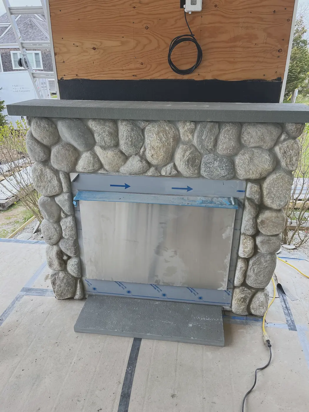 Outdoor fireplace under construction — fieldstone face, bluestone mantel and hearth